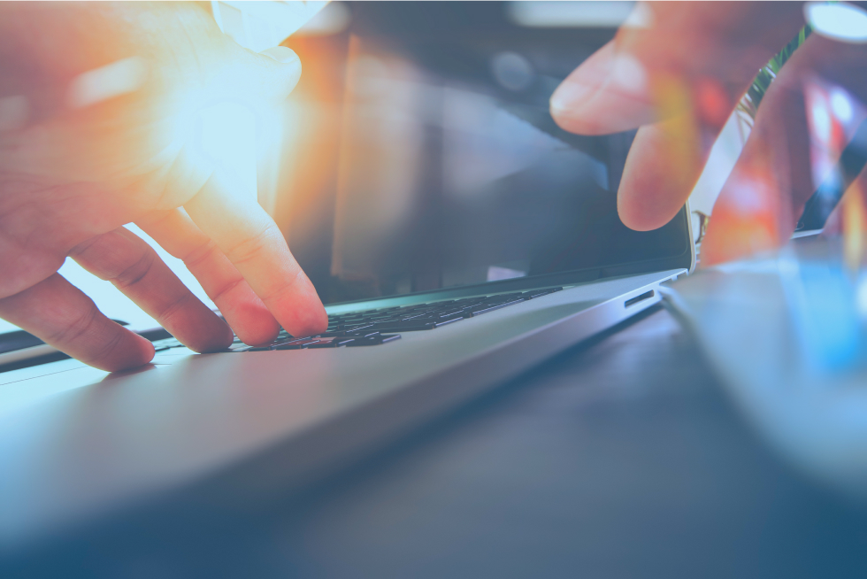 逆光の中でパソコン作業をする手元。落ち着いた雰囲気の中でのWEBデザイン作業。